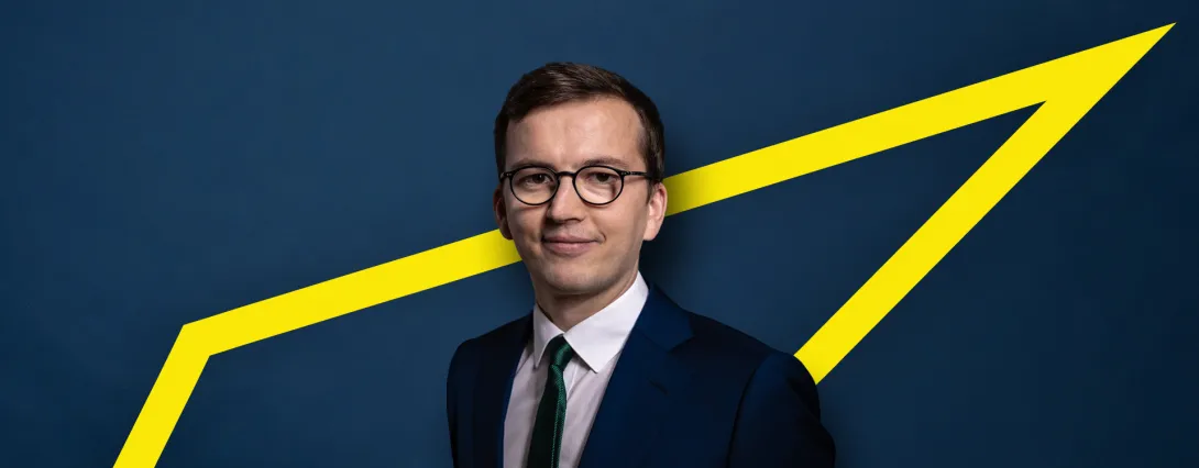 Portrait of Nils Schlenkhoff against a dark blue background with a yellow arrow motif.